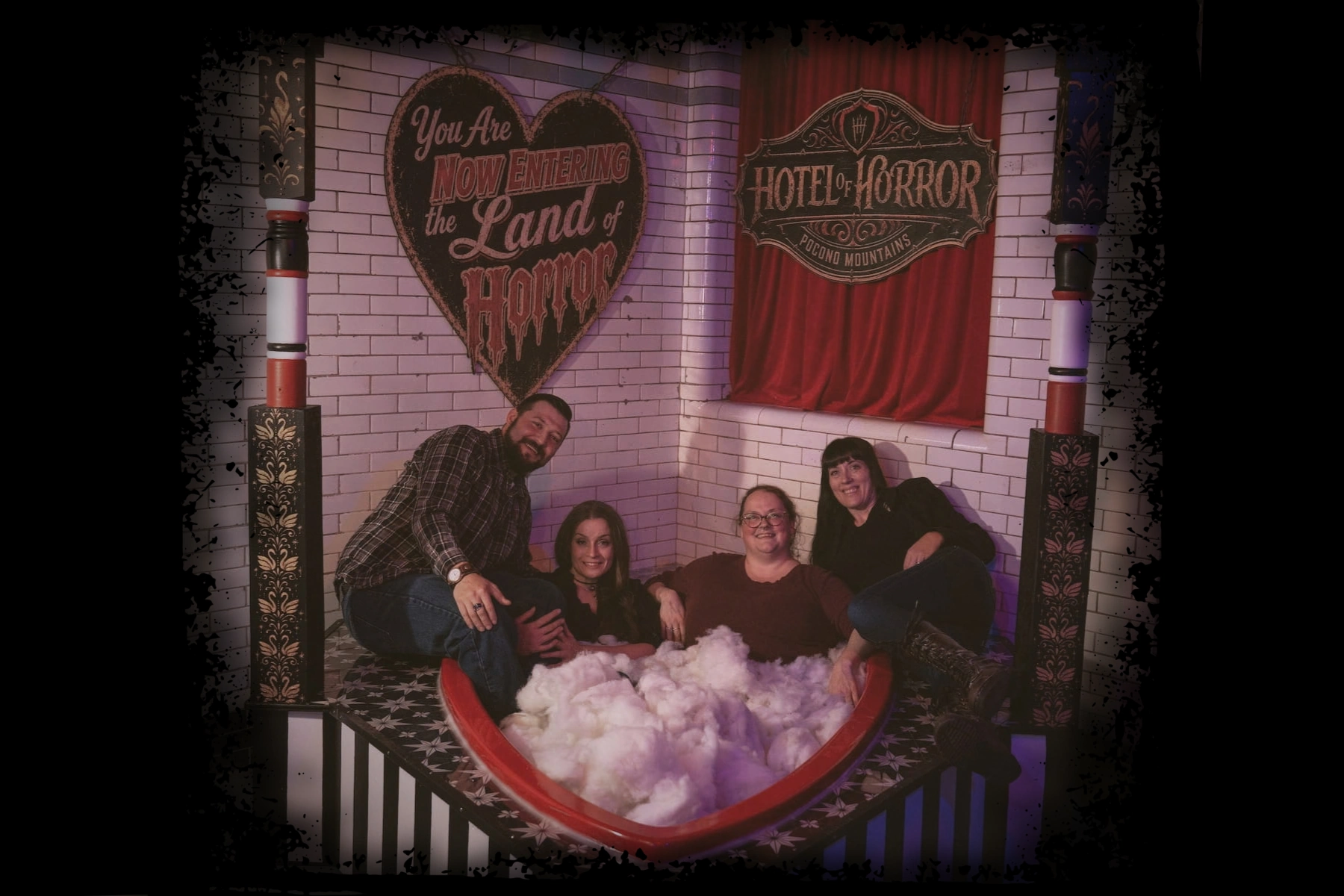 Group of friends posing in the Poconos heart shaped tub of the Hotel of Horror Haunted House